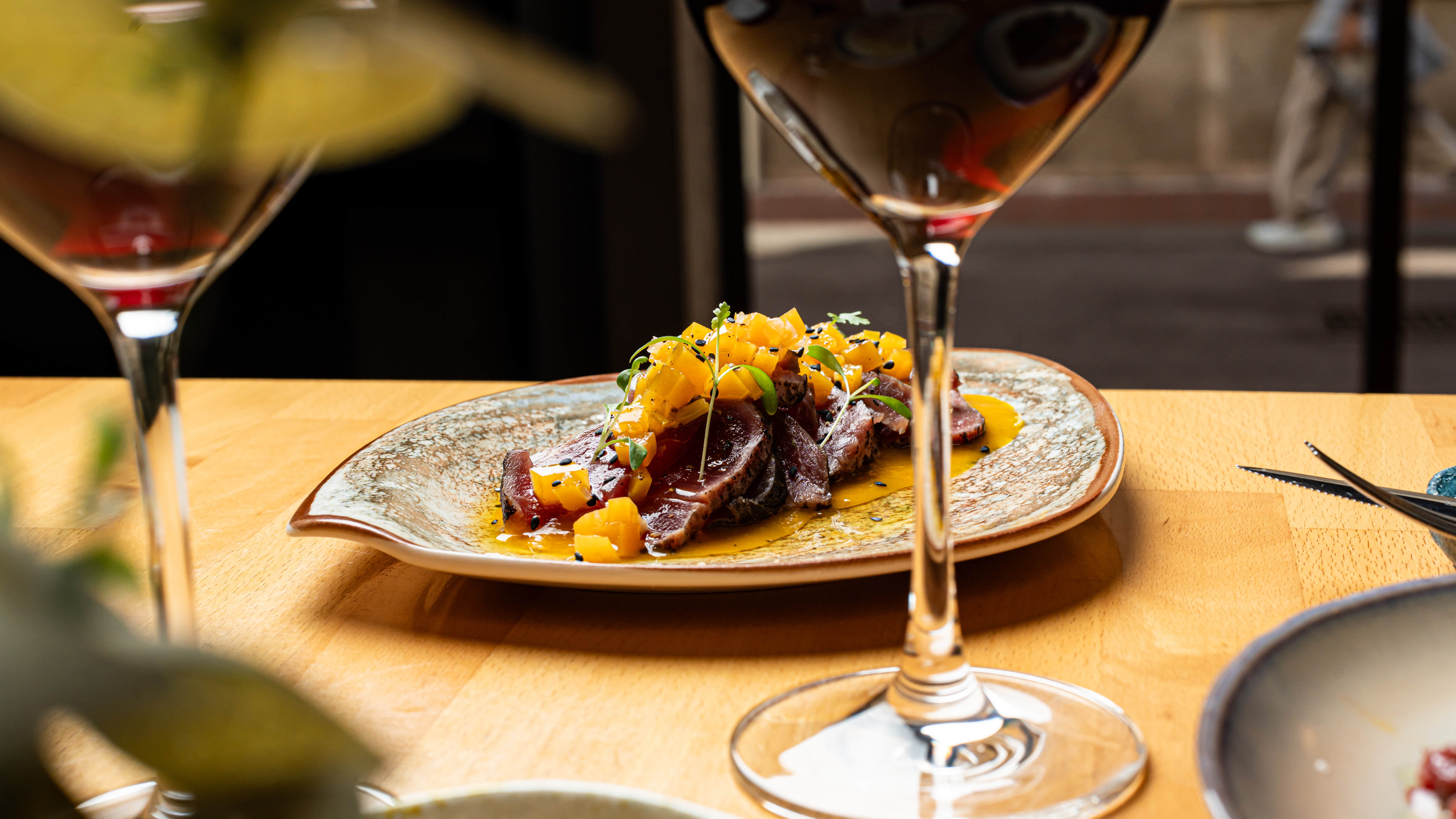 Plato servido con copas de vino en Més de Vi, experiencia gastronómica ideal para una tarjeta regalo restaurante en Barcelona.